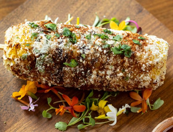 Elote grilled corn on the cob dipped in Little BEEst Sneaker Green Jalapeño Hot Honey Sauce & cotija cheese